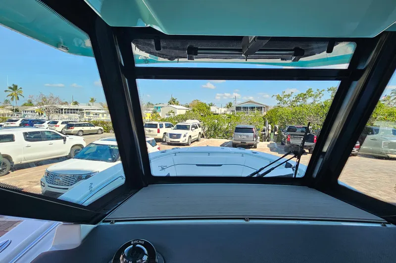 Slide: The Image of View from 2022 Blackfin 272 CC boat cockpit, overlooking parked cars and tropical scenery. - 26