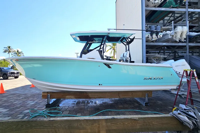 Slide: The Image of 2022 Blackfin 272 CC boat in light blue, docked outdoors on a sunny day. - 8