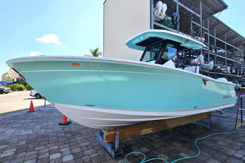 Slide: The Image of 2022 Blackfin 272 CC boat in light blue, docked outdoors on a sunny day. - 9