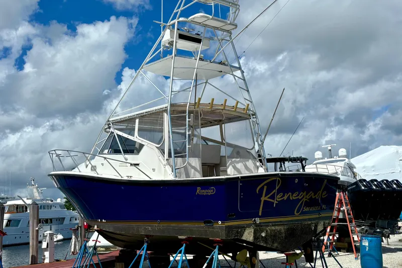 The Image of 1990 Rampage 36 Express boat named "Renegade" on stands at a marina. - 1