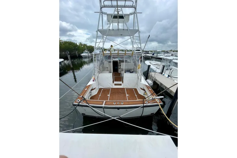 Slide: The Image of 1990 Rampage 36 Express boat docked, featuring wooden deck and tower under cloudy skies. - 11