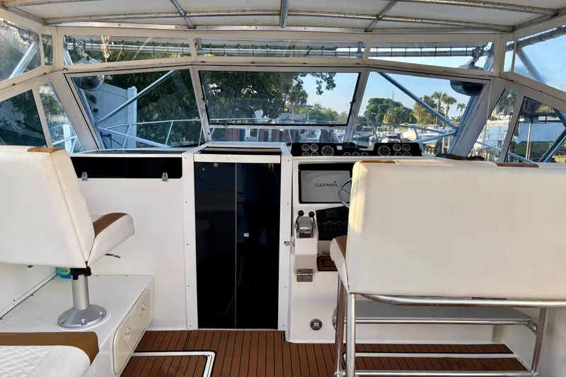 Slide: The Image of Interior view of a 1990 Rampage 36 Express boat cockpit with white seating and navigation equipment. - 3