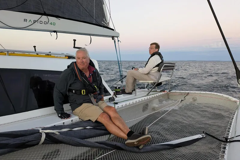 Slide: The Image of Two people sailing on a 2023 Rapido 40 trimaran at sea during sunset. - 6