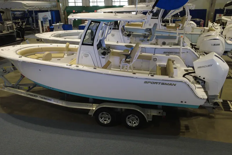Slide: The Image of 2026 Sportsman Heritage 231 Center Console boat displayed indoors on a trailer. - 2