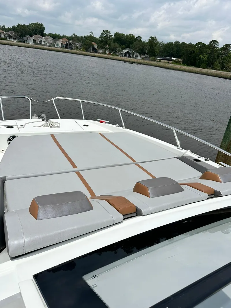 Slide: The Image of 2021 Beneteau GT 32 boat with spacious sunbathing deck, docked by a serene waterfront. - 15