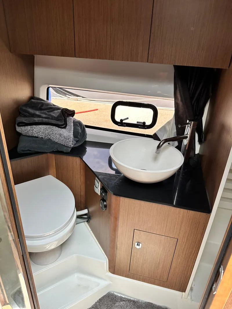 Slide: The Image of 2021 Beneteau GT 32 bathroom with modern sink, toilet, and wooden cabinetry. - 44