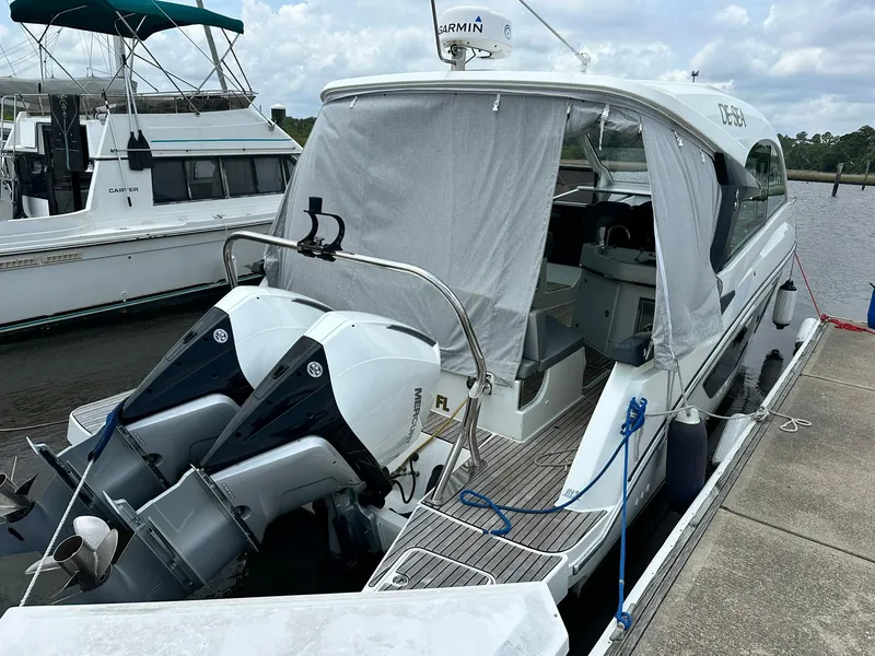 Slide: The Image of 2021 Beneteau GT 32 boat docked, featuring twin outboard engines and covered cockpit. - 5