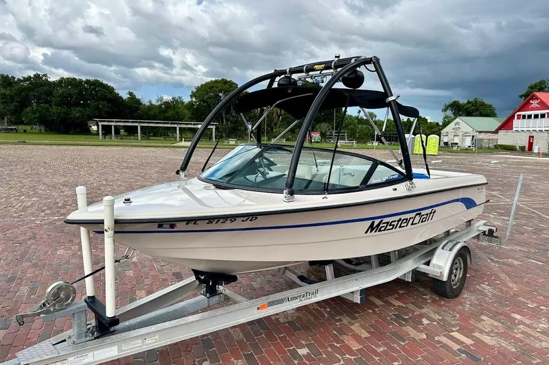 The Image of 1998 MasterCraft SportStar 19 boat on trailer, parked on brick pavement under cloudy sky. - 1