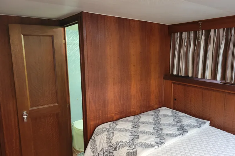 Slide: The Image of 1977 Hatteras 43 Double Cabin interior with wood paneling and bed, adjacent bathroom. - 10