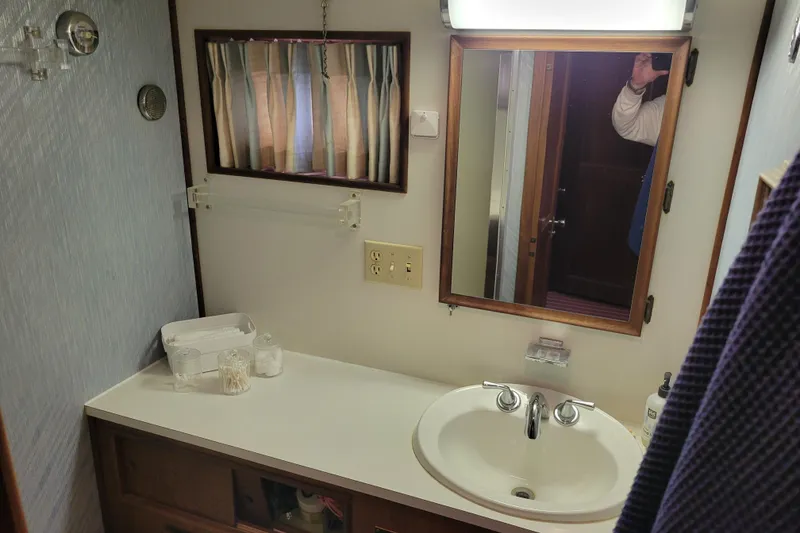 Slide: The Image of 1977 Hatteras 43 Double Cabin bathroom with sink, mirror, and toiletries. - 11