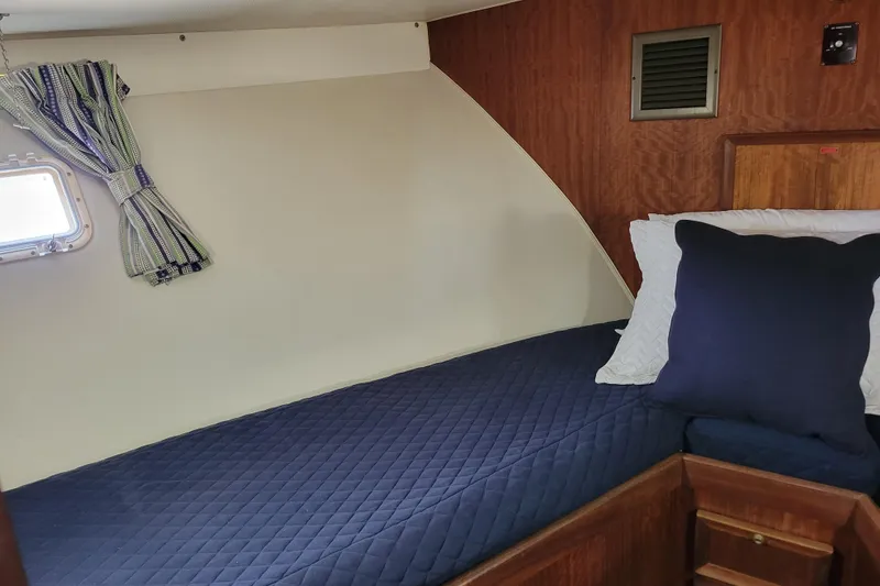 Slide: The Image of Cozy cabin interior of 1977 Hatteras 43 Double Cabin with blue bedding and striped curtains. - 13