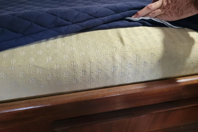 Slide: The Image of Hand lifting blue quilt on Hatteras 43 Double Cabin 1977 bed. - 16