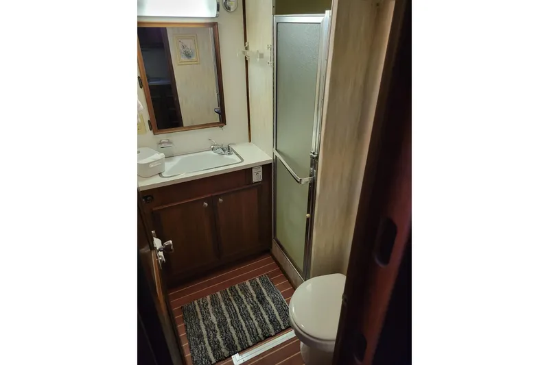 Slide: The Image of 1977 Hatteras 43 Double Cabin bathroom with shower, sink, and wooden cabinetry. - 17