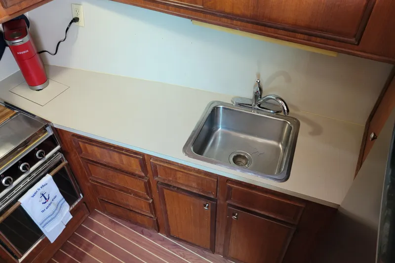 Slide: The Image of 1977 Hatteras 43 Double Cabin kitchen with sink, stove, and wooden cabinets. - 19