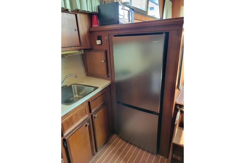 Slide: The Image of 1977 Hatteras 43 Double Cabin kitchen with stainless steel fridge and wooden cabinetry. - 20