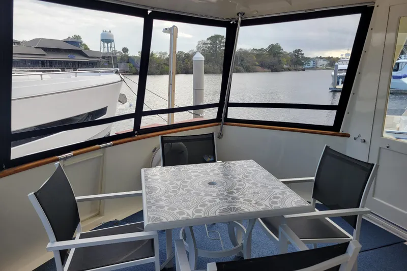 Slide: The Image of 1977 Hatteras 43 Double Cabin yacht interior with table and chairs, overlooking marina. - 33