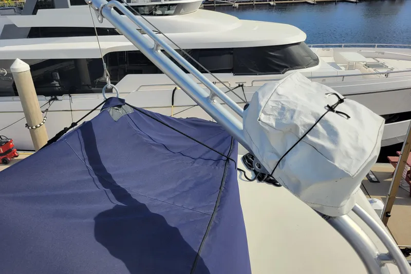 Slide: The Image of 1977 Hatteras 43 Double Cabin with blue canopy and docked yacht in background. - 44