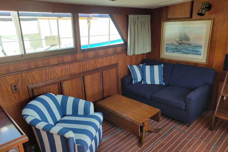Slide: The Image of Interior of 1977 Hatteras 43 Double Cabin with striped chair, blue sofa, and nautical decor. - 5