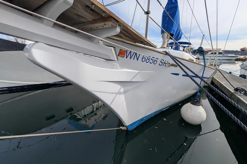 Slide: The Image of 1980 Island Trader 38 sailboat docked, featuring sleek white hull and blue sail cover. - 2