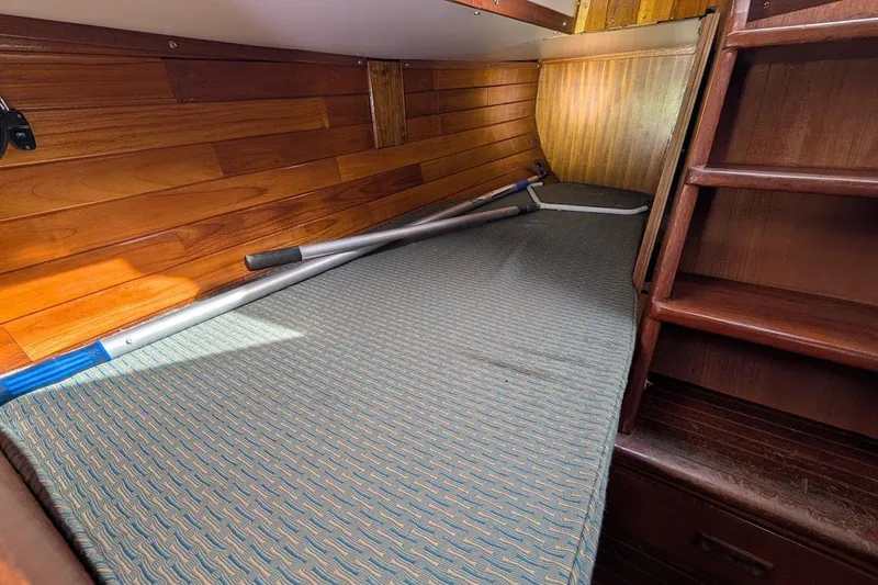 Slide: The Image of Interior cabin of 1980 Island Trader 38 sailboat with wooden paneling and a cushioned berth. - 21