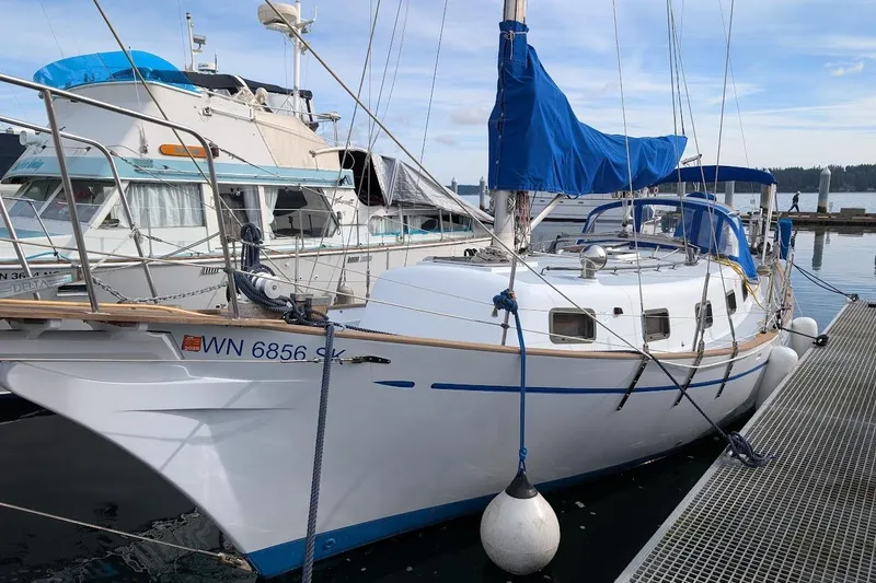 Slide: The Image of 1980 Island Trader 38 sailboat docked, featuring blue sail covers and white hull. - 3