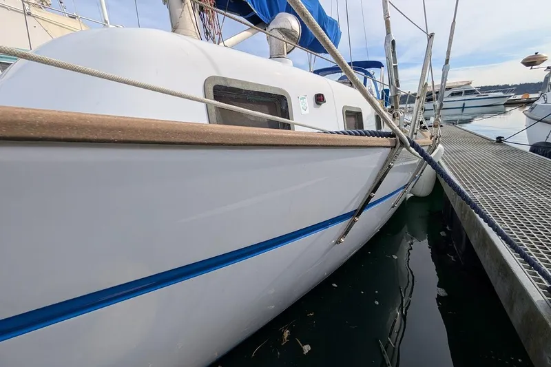 Slide: The Image of 1980 Island Trader 38 sailboat docked at marina, featuring sleek white hull and blue accents. - 4