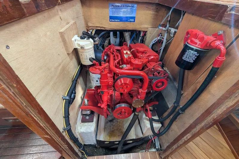 Slide: The Image of Engine compartment of a 1980 Island Trader 38 sailboat, featuring a red marine engine. - 49