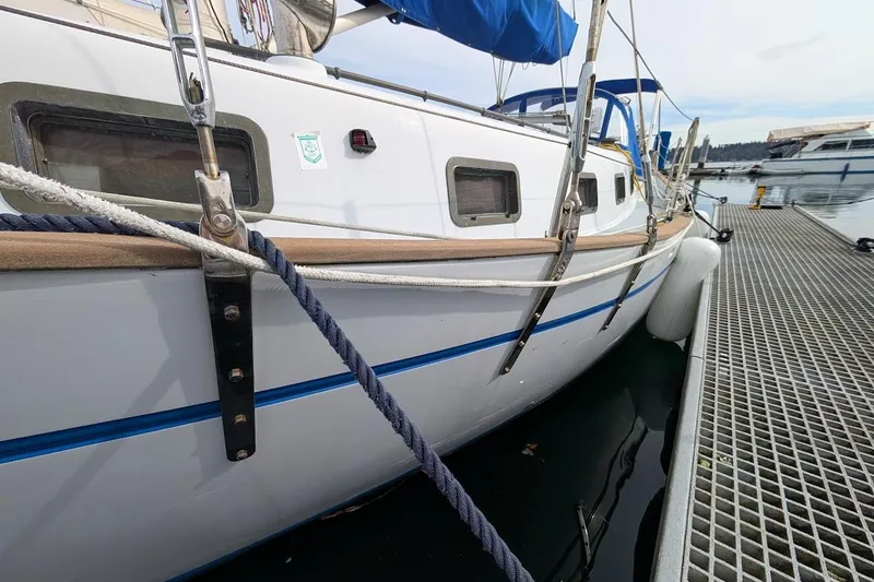 Slide: The Image of 1980 Island Trader 38 sailboat docked, featuring blue accents and sturdy rigging. - 5