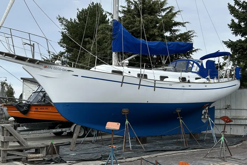 Slide: The Image of 1980 Island Trader 38 sailboat on stands, blue and white hull, docked outdoors. - 53