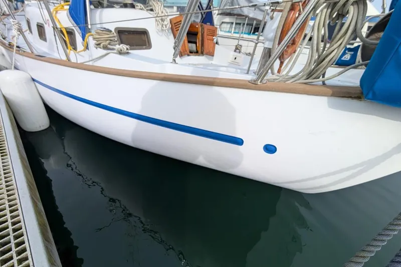 Slide: The Image of 1980 Island Trader 38 sailboat docked, featuring white hull with blue accents and nautical equipment. - 6