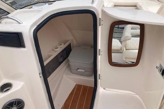 Slide: The Image of 2023 Grady-White Freedom 215 boat interior with compact restroom and seating area. - 11