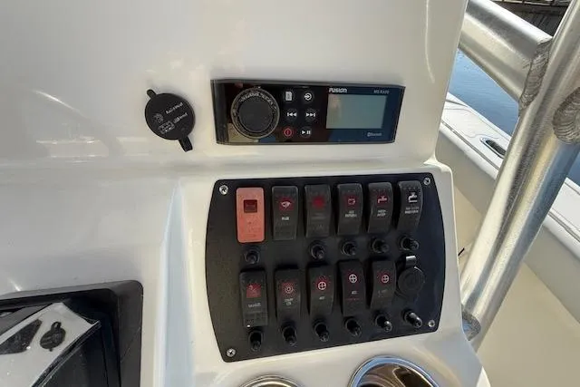 Slide: The Image of Control panel of a 2019 Mako 214 Center Console boat with switches and a Fusion stereo. - 15
