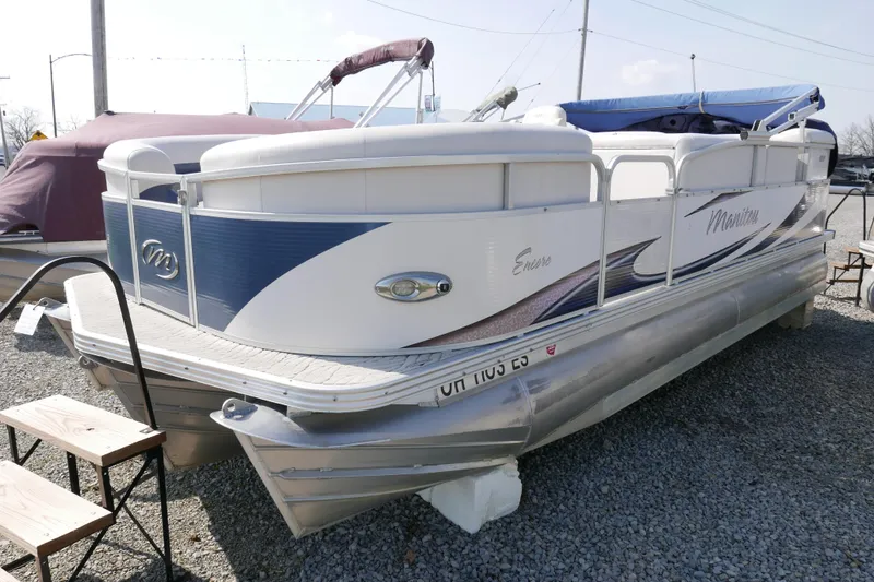 Slide: The Image of 2009 Manitou 20 Encore pontoon boat on display in a gravel lot. - 2