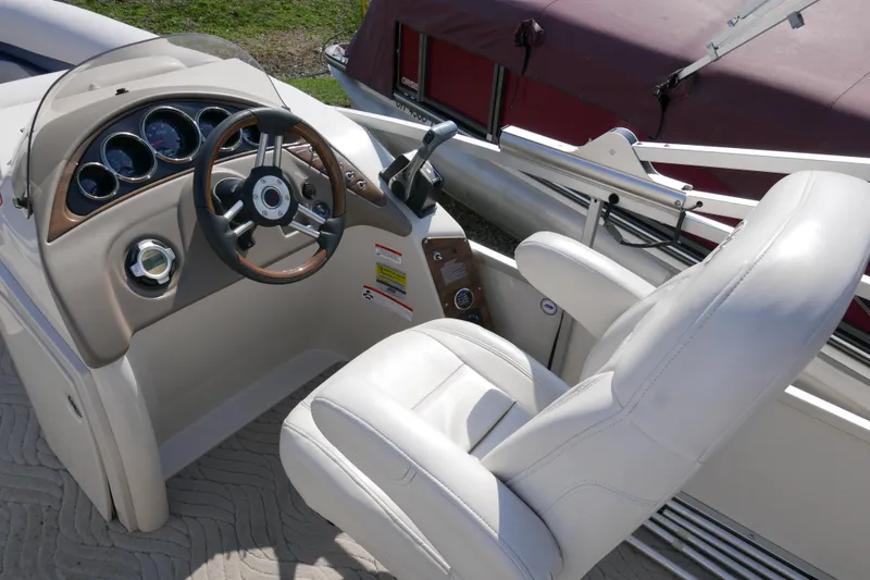 Slide: The Image of 2009 Manitou 20 Encore boat cockpit with steering wheel and white captain's chair. - 8