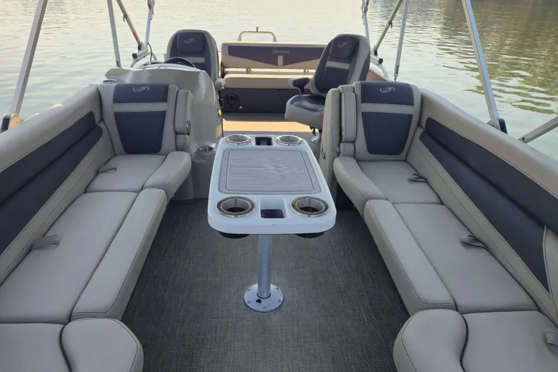 Slide: The Image of 2022 Barletta Cabrio 24UC pontoon boat interior with seating and table on calm water. - 12
