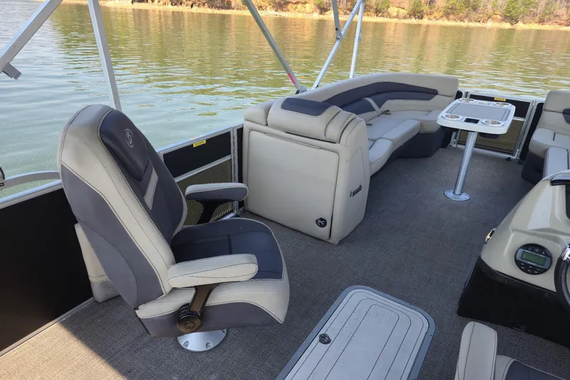 Slide: The Image of 2022 Barletta Cabrio 24UC pontoon boat interior with plush seating and table on a lake. - 15
