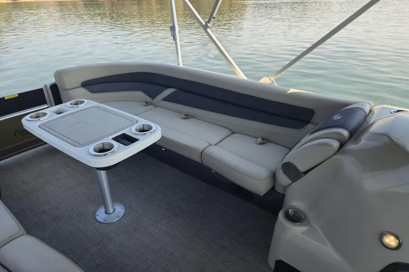 Slide: The Image of 2022 Barletta Cabrio 24UC boat interior with seating and table on calm water. - 16