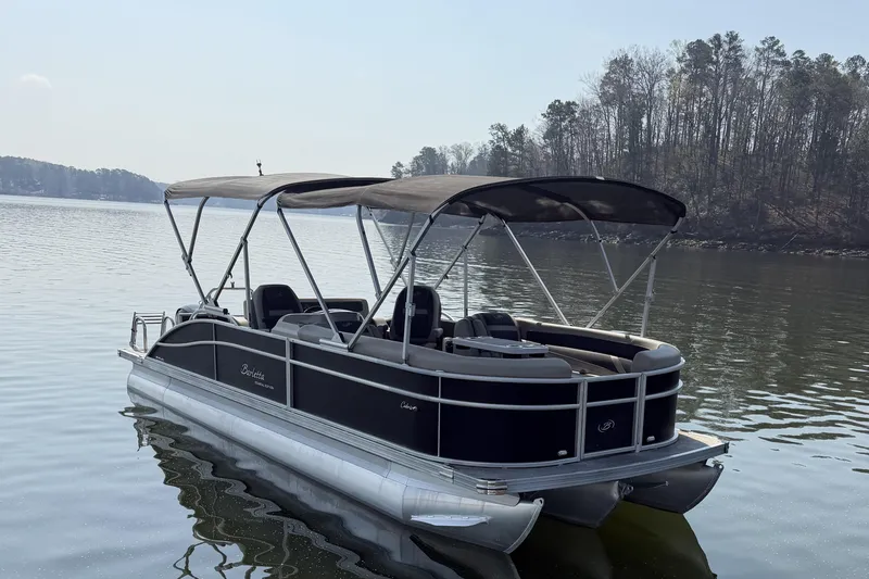 Slide: The Image of 2022 Barletta Cabrio 24UC pontoon boat on a calm lake with trees in the background. - 3
