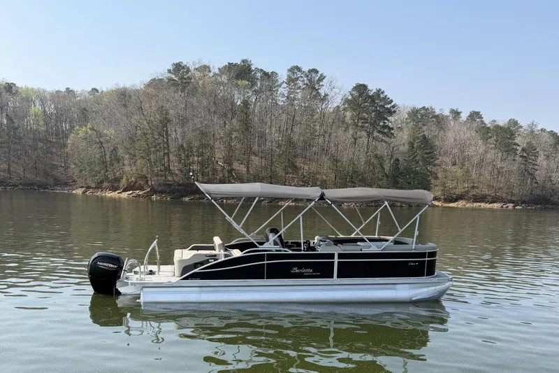 Slide: The Image of 2022 Barletta Cabrio 24UC pontoon boat on a calm lake with forested shoreline. - 5