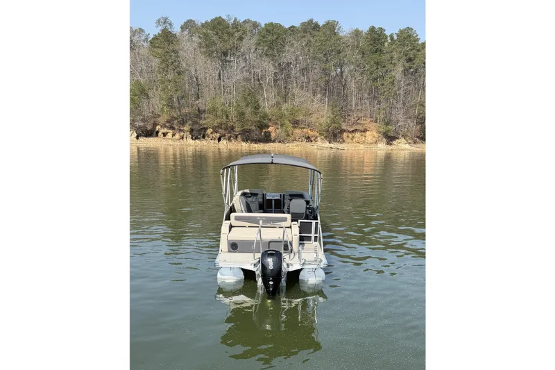 Slide: The Image of 2022 Barletta Cabrio 24UC pontoon boat on a calm lake with forested shoreline. - 7