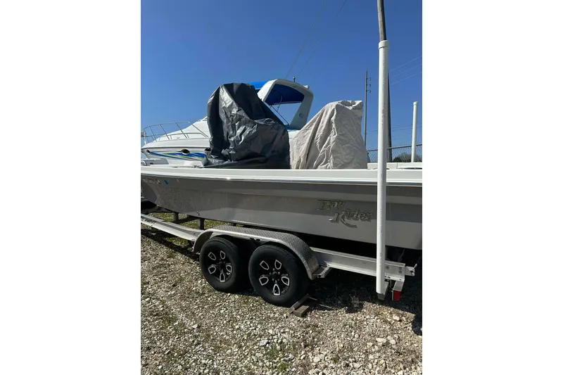 Slide: The Image of 2022 BayRider Kencraft 219 Bay boat on trailer, covered, under clear blue sky. - 20