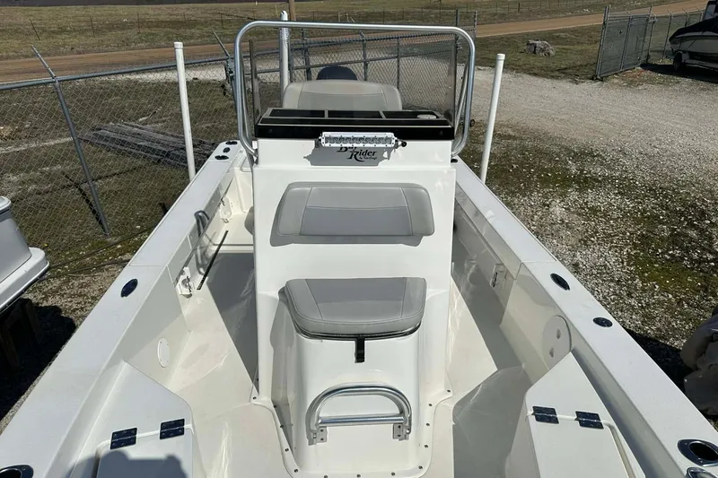 Slide: The Image of 2022 BayRider Kencraft 219 Bay boat interior with seating and console, parked outdoors. - 45