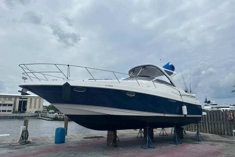 Slide: The Image of 2008 Regal 38 Express boat on dry dock, blue and white hull, cloudy sky background. - 2