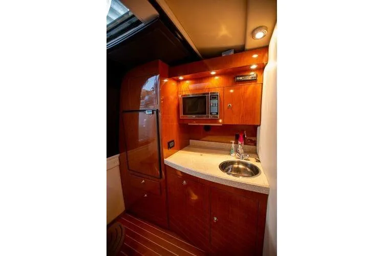 Slide: The Image of Compact kitchen area in a 2008 Regal 38 Express yacht with wood cabinetry and modern appliances. - 23