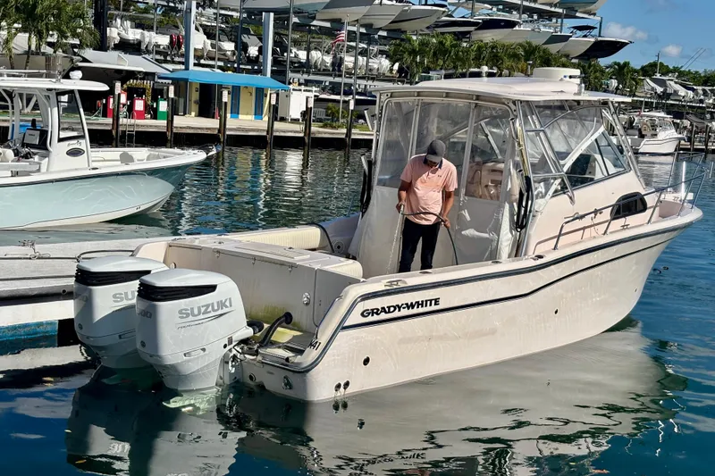 Slide: The Image of 2007 Grady-White Marlin 300 boat docked with Suzuki engines, man handling ropes. - 2