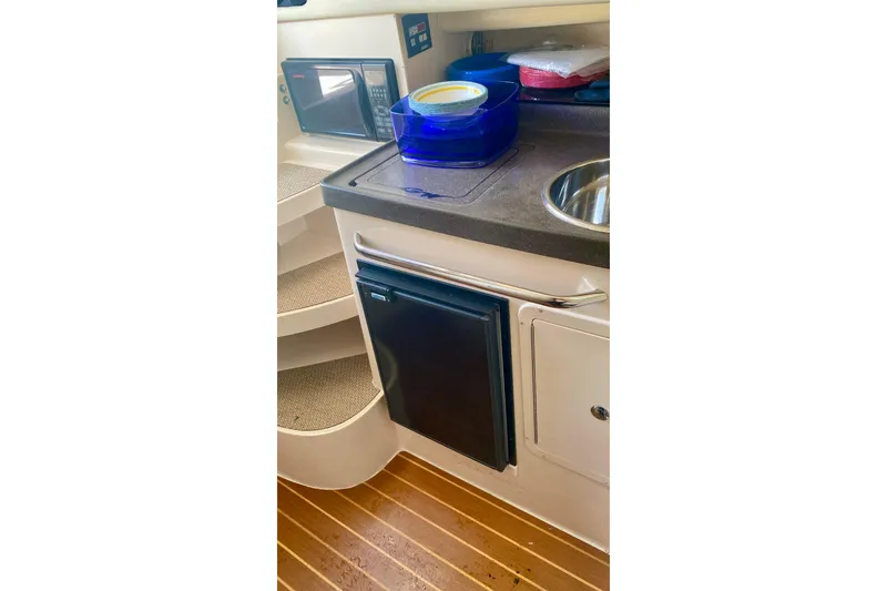 Slide: The Image of 2007 Grady-White Marlin 300 interior with kitchenette, featuring a compact fridge and sink. - 4