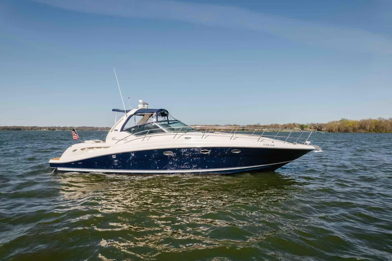 The Image of 2003 Sea Ray 420 Sundancer yacht cruising on a serene lake under clear skies. - 0