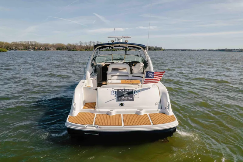 Slide: The Image of 2003 Sea Ray 420 Sundancer docked, featuring teak swim platform and American flag. - 33