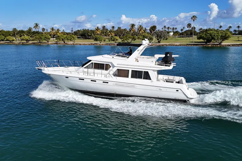 The Image of 2003 Navigator Rival yacht cruising on a scenic waterway with lush greenery. - 1