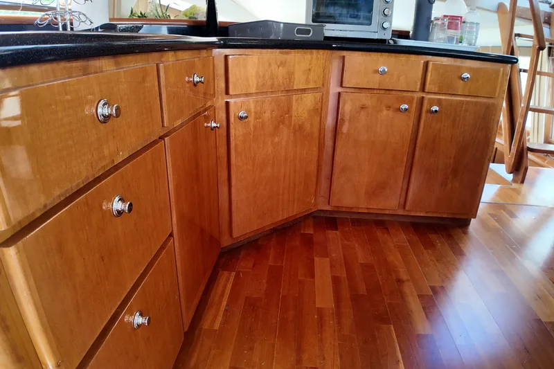 Slide: The Image of Wooden kitchen cabinets with chrome knobs, black countertop, and hardwood flooring. - 27